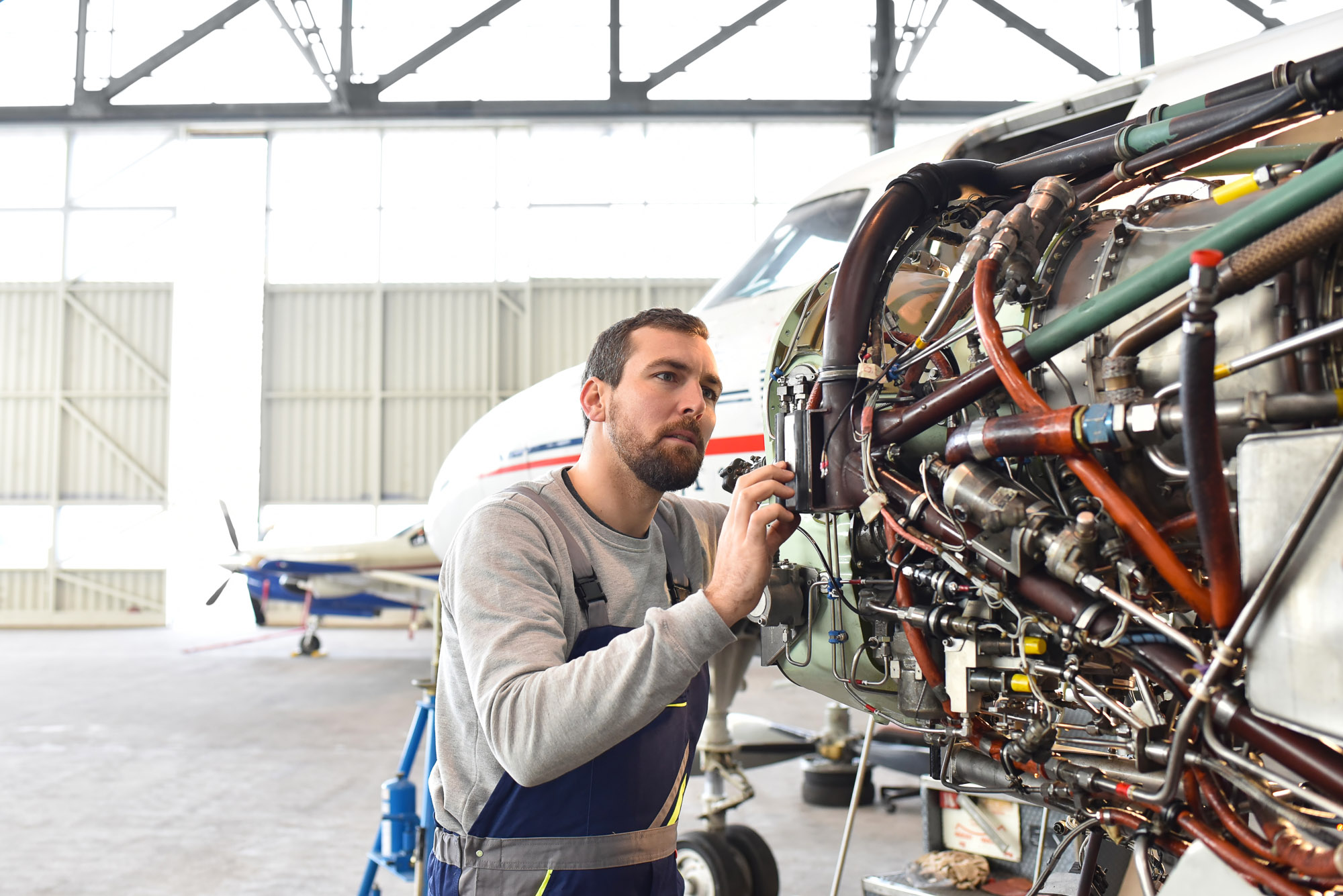 Aircraft mechanic inspecting and reviewing documentation for a replacement aircraft part in a hangar