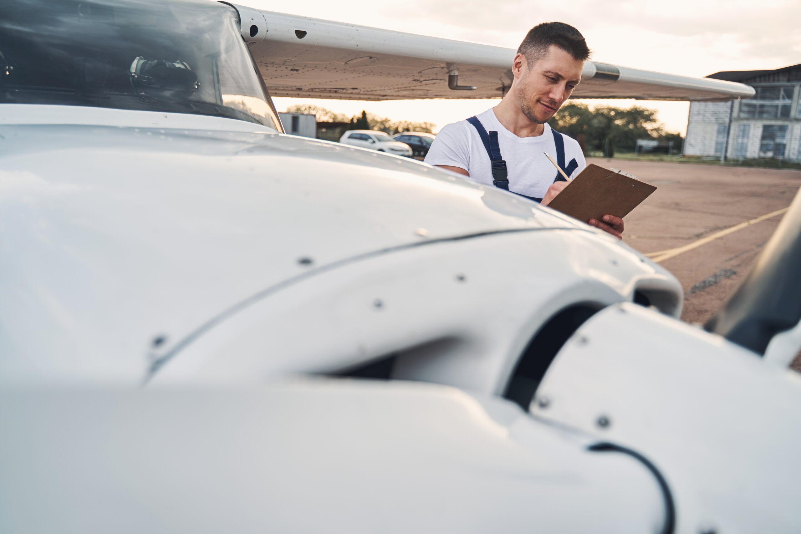 A mechanic reviewing and organizing a stack of Service Bulletins and Airworthiness Directives in an airplane hangar